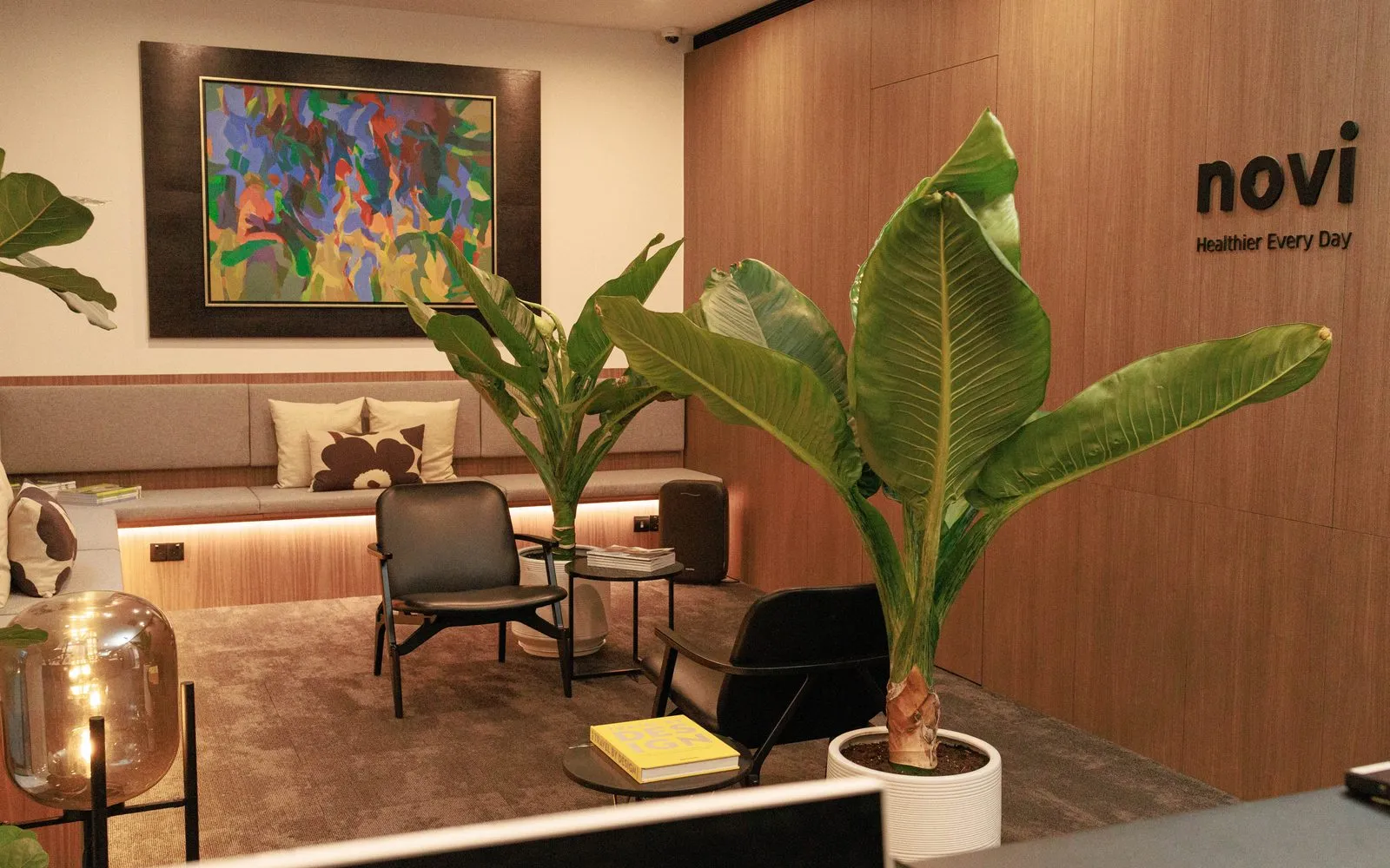 The NOVI Health clinic interior — a warm waiting area with wood paneling and plants.